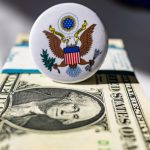 A white button sitting on top of a one dollar bill