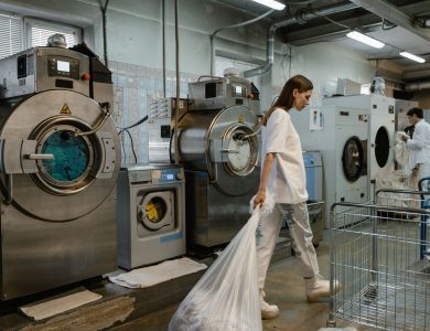 Busy industrial laundry with workers handling large washing machines.