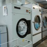 Interior view of industrial laundry machines in a facility with linens being washed.