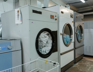 Interior view of industrial laundry machines in a facility with linens being washed.