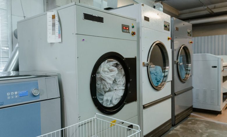 Interior view of industrial laundry machines in a facility with linens being washed.