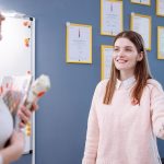 Smiling woman in a pink sweater engaging in conversation in an office environment.