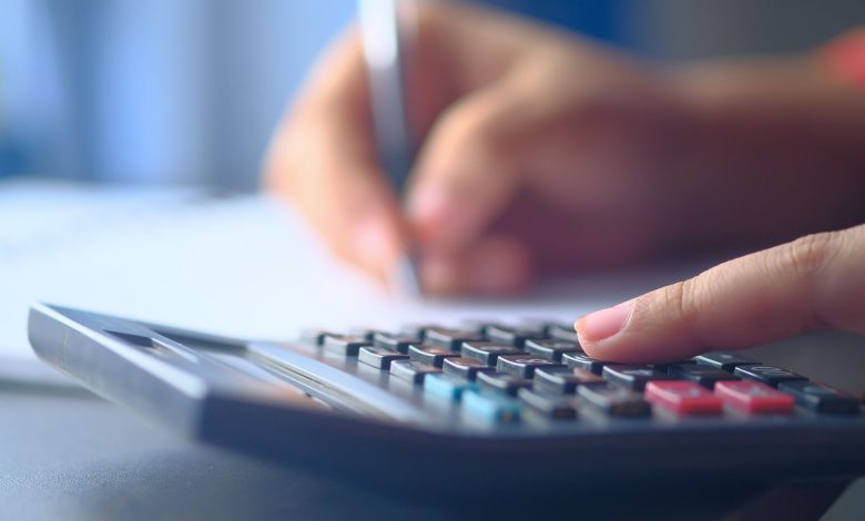 A close-up image of hands working on a calculator and writing, representing budgeting and financial planning.
