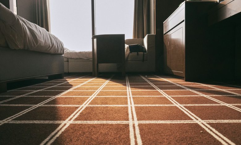 Low-angle view of a sunlit bedroom with patterned carpet and modern furniture, creating a warm atmosphere.