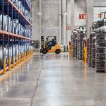 A forklift operates in an industrial warehouse with stacked goods. Efficient distribution setting.