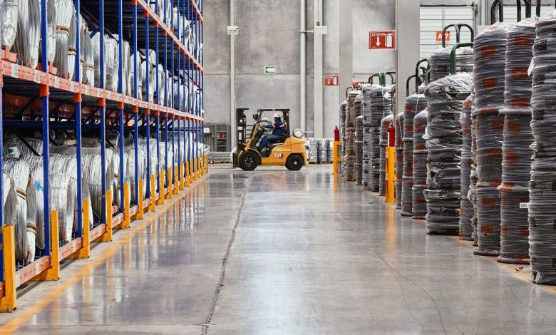A forklift operates in an industrial warehouse with stacked goods. Efficient distribution setting.