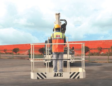 A worker in safety gear operates an ACE man lift crane, showcasing industrial safety in an outdoor setting.