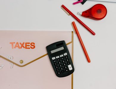 Flat lay image featuring a calculator, pens, and a folder labeled 'TAXES', perfect for finance-related themes.