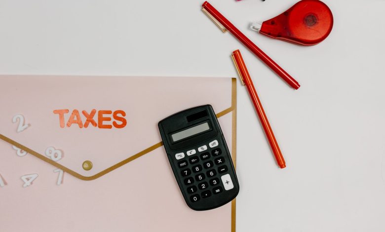 Flat lay image featuring a calculator, pens, and a folder labeled 'TAXES', perfect for finance-related themes.