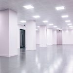 Wide-angle view of a modern minimalist white office space with clean lines and ample lighting.
