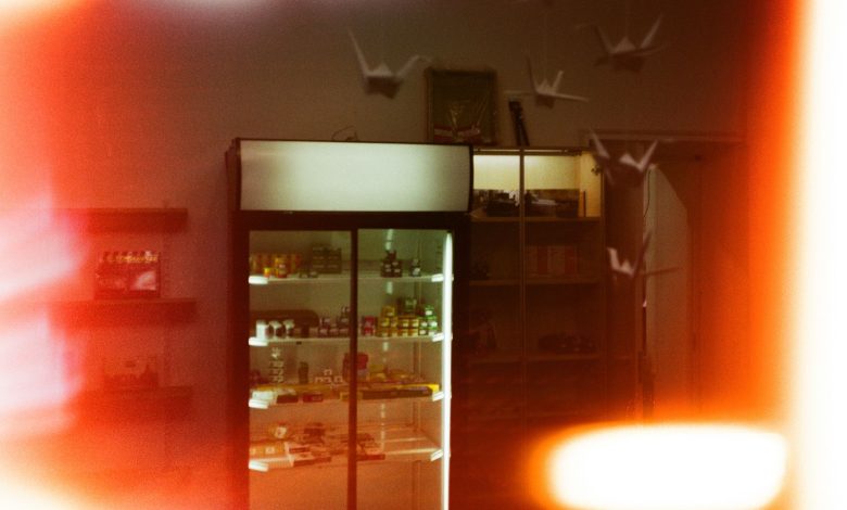 Dimly lit shop interior featuring a refrigerated display and hanging paper cranes.