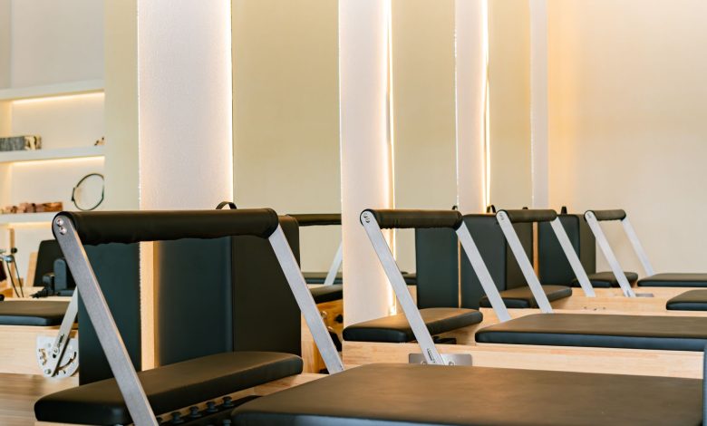 Interior of a modern Pilates studio featuring multiple reformer machines in a calming atmosphere.