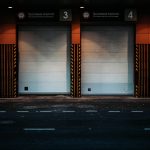 Gates of modern garage located near asphalt road in evening in contemporary city