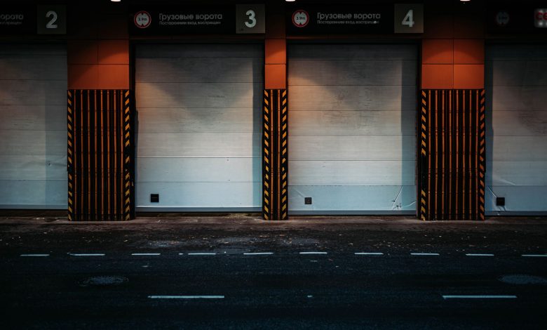 Gates of modern garage located near asphalt road in evening in contemporary city