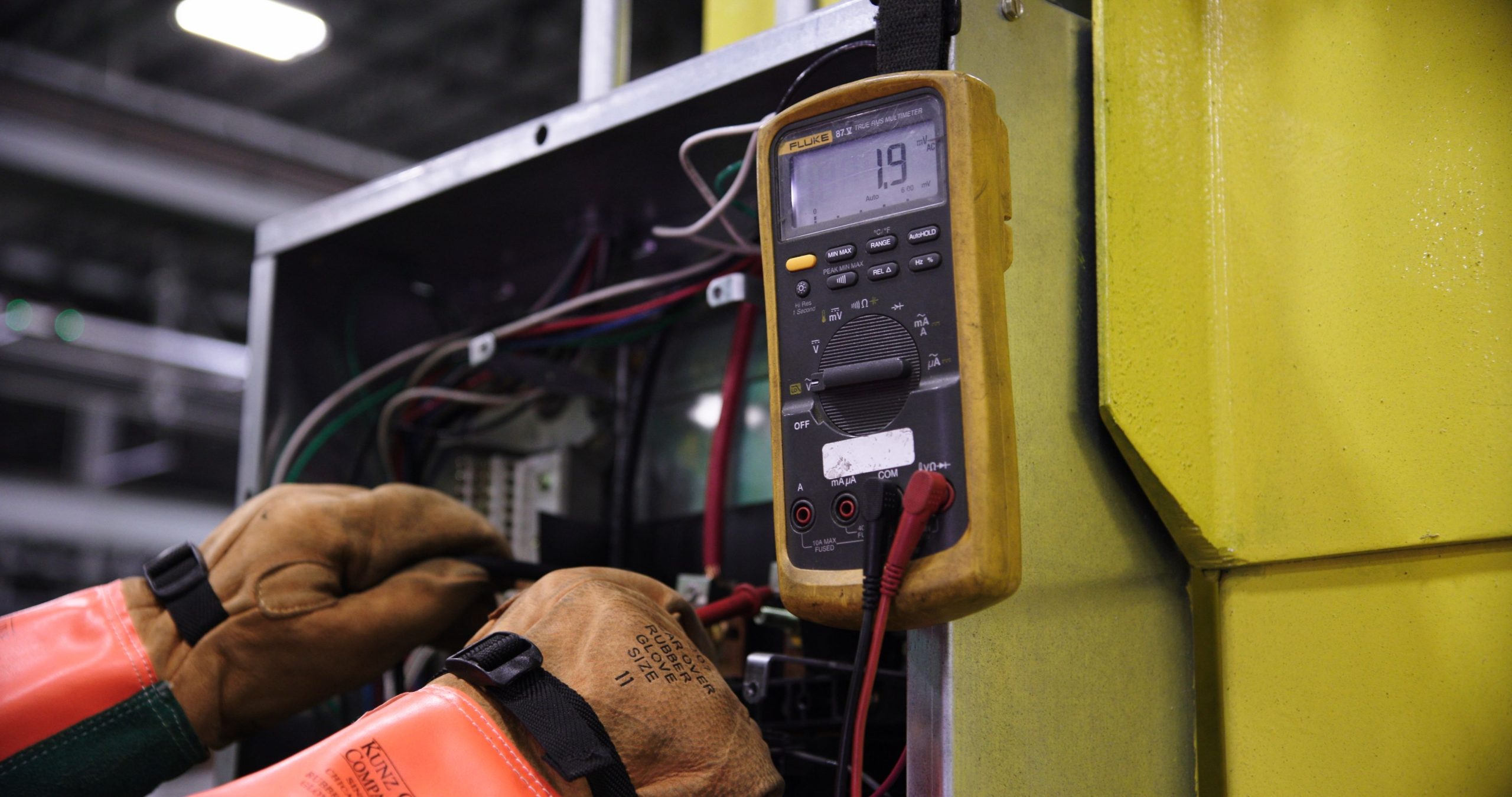 Electrician using a multimeter to test wiring in an electrical panel.