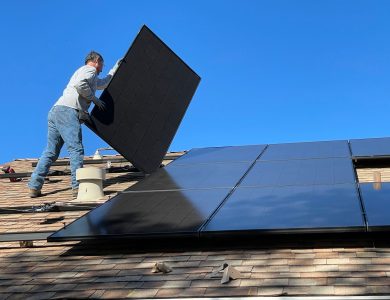 A worker installs solar panels on a sunny day, highlighting renewable energy solutions.