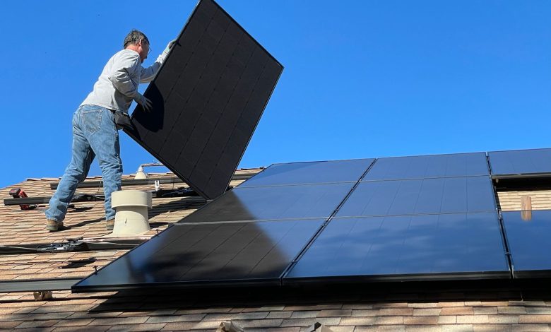 A worker installs solar panels on a sunny day, highlighting renewable energy solutions.