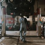 Automobile mechanic fixing a car in a repair garage, focus on service and repair work