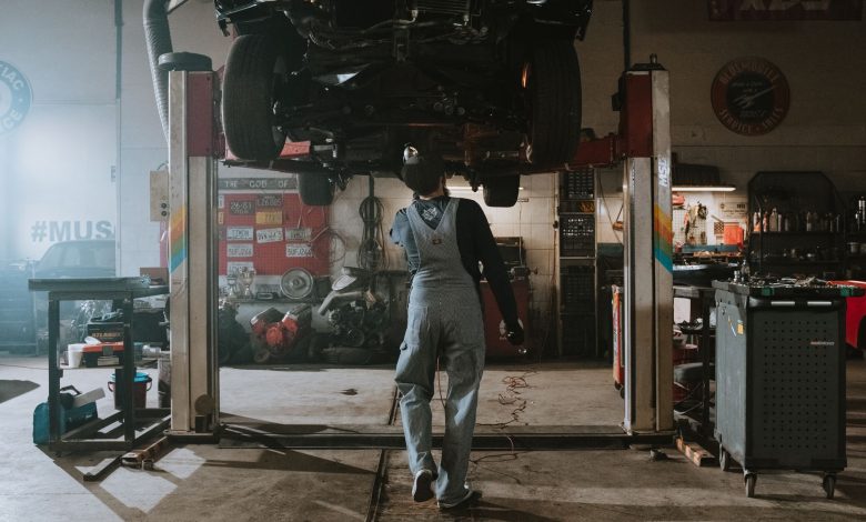 Automobile mechanic fixing a car in a repair garage, focus on service and repair work