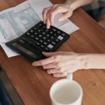 A woman uses a calculator to manage finances at home, focused on budget planning.