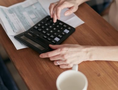 A woman uses a calculator to manage finances at home, focused on budget planning.