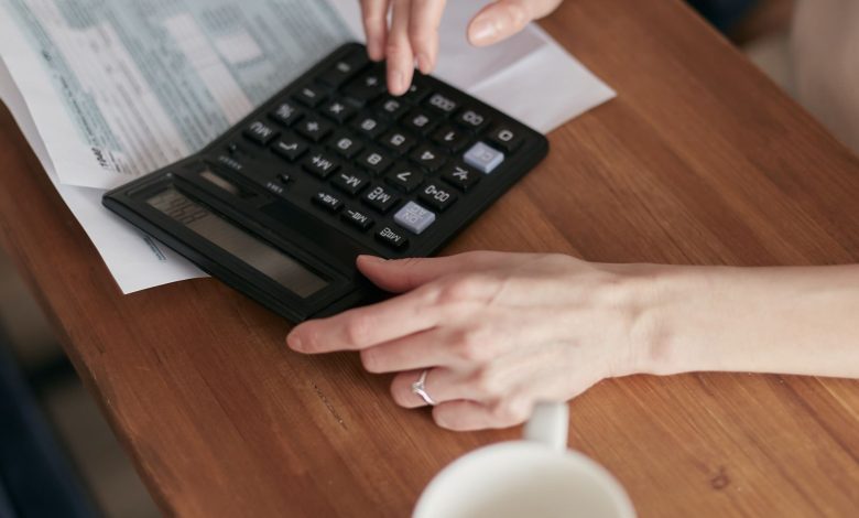 A woman uses a calculator to manage finances at home, focused on budget planning.