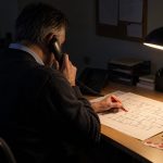 A care-home premises manager sits alone in the facilities office after the monthly emergency-lighting test, placing