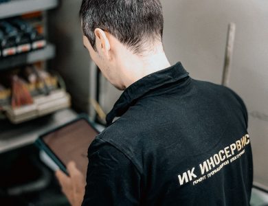 Electrician inspecting a circuit panel indoors.