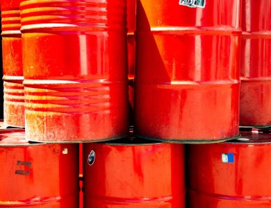 Bright red industrial oil barrels stacked outdoors in daylight, showcasing vivid color and industrial theme.