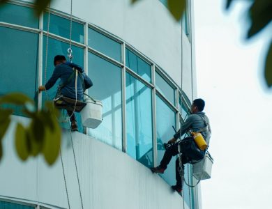 Window cleaners suspended on ropes clean a high-rise building's glass exterior.
