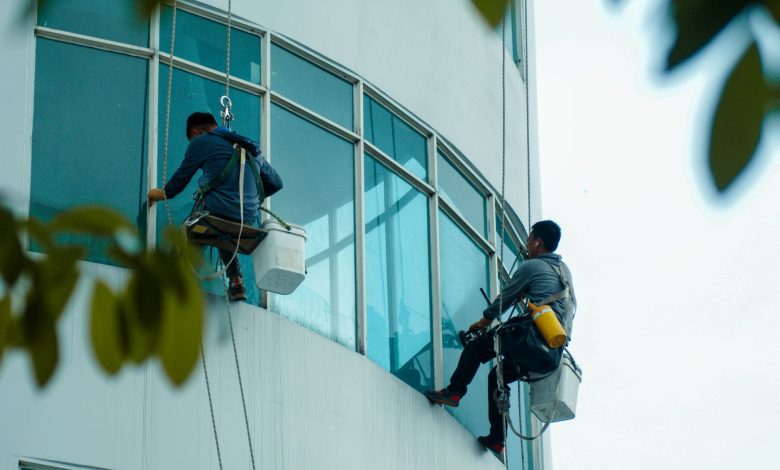 Window cleaners suspended on ropes clean a high-rise building's glass exterior.