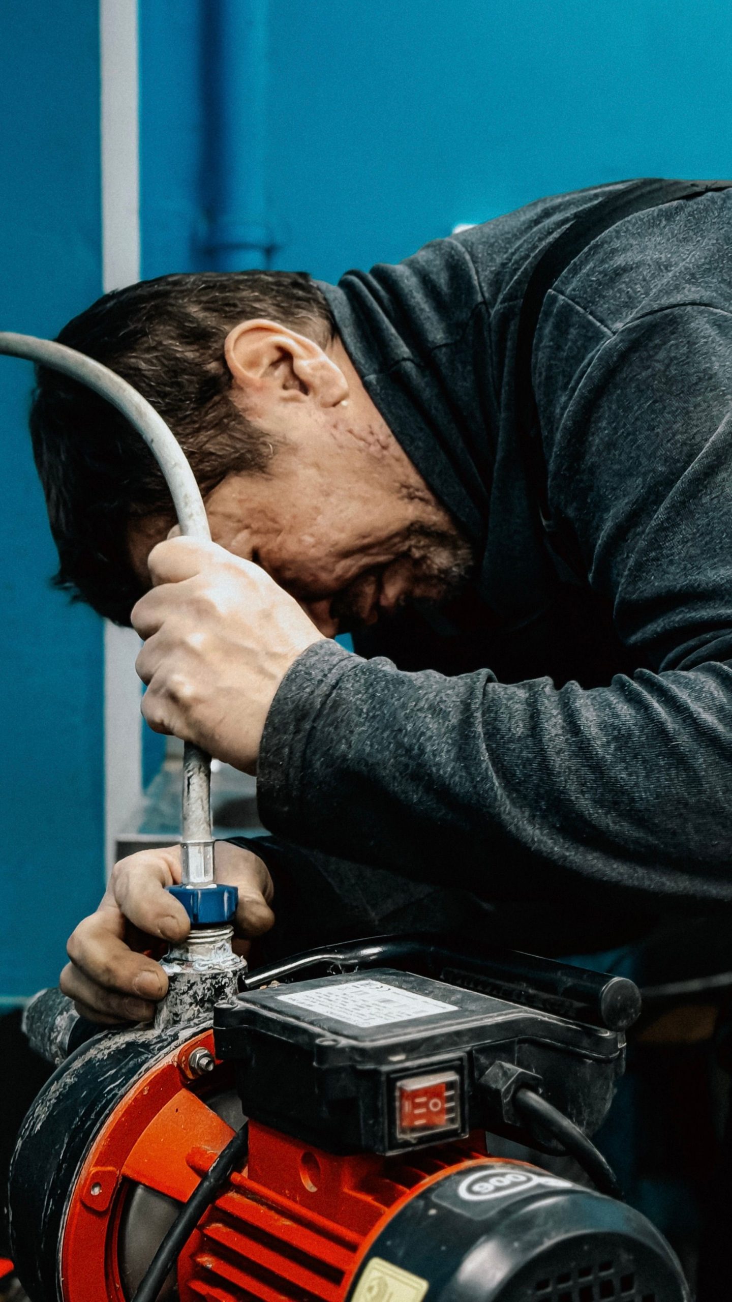 Technician inspecting and adjusting a water pump indoors.