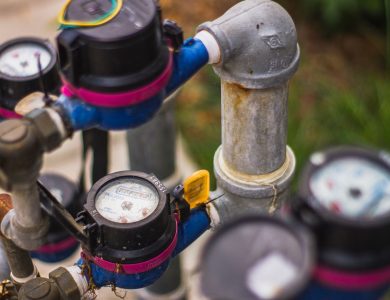 Detailed image of industrial water pressure gauges and pipes in an outdoor setting.
