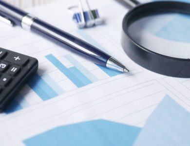 Close-up of calculator, pen, and magnifying glass on financial documents.