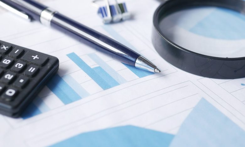Close-up of calculator, pen, and magnifying glass on financial documents.
