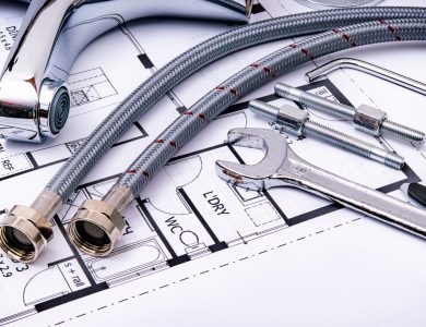 Close-up of plumbing tools and faucet on top of an architectural blueprint, perfect for hardware and construction themes.