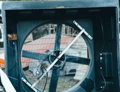 Close-up of a vintage industrial fan amidst outdoor junkyard setting, conveying industrial decay.
