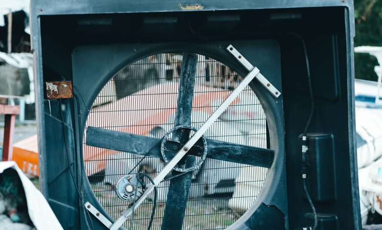 Close-up of a vintage industrial fan amidst outdoor junkyard setting, conveying industrial decay.