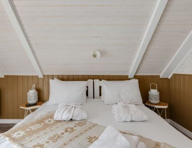 Inviting attic bedroom with cozy bedding and bathrobes on a white bed, perfect for relaxation.
