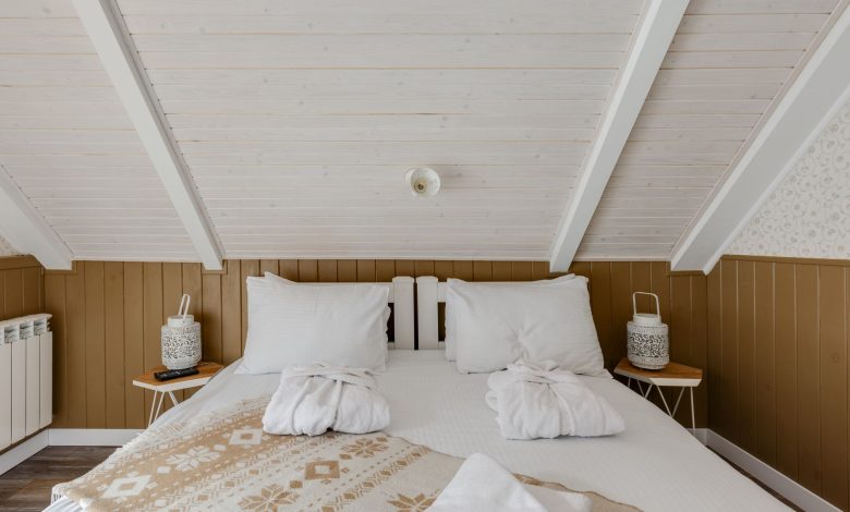 Inviting attic bedroom with cozy bedding and bathrobes on a white bed, perfect for relaxation.