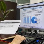 Person analyzing financial data on a computer screen in an office setting.