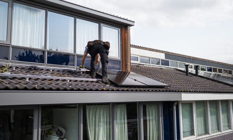 Technician working on installing solar panels on a residential rooftop during the day.