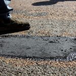 Close-up view of a freshly patched road section with work boots in South Africa.