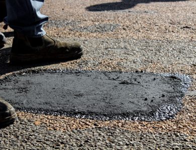 Close-up view of a freshly patched road section with work boots in South Africa.