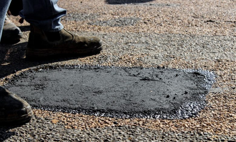 Close-up view of a freshly patched road section with work boots in South Africa.