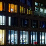 Night view of a modern office building facade with illuminated windows showcasing varied interior lighting.