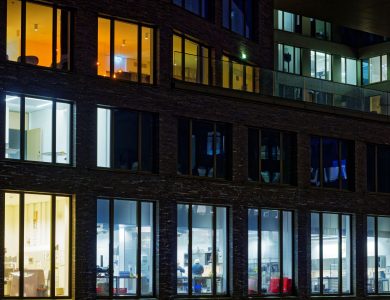 Night view of a modern office building facade with illuminated windows showcasing varied interior lighting.