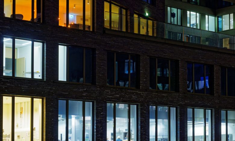 Night view of a modern office building facade with illuminated windows showcasing varied interior lighting.