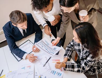 A diverse team in business attire collaborates over graphs and charts for a successful project.