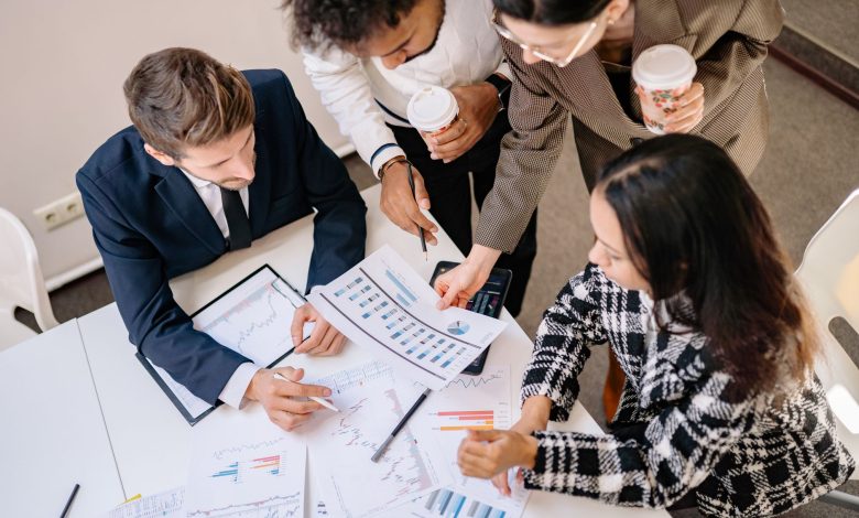 A diverse team in business attire collaborates over graphs and charts for a successful project.